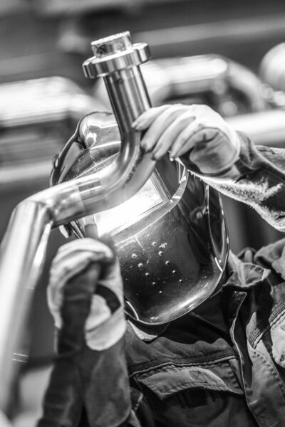 Industrial worker welding in metal factory.